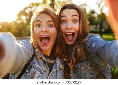 Portrait of two excited young girls making funny faces while taking a selfie outdoors - Shutterstock ID 736592197