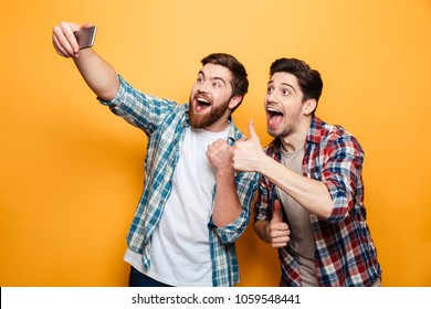 Portrait of a two excited young men taking a selfie while standing together isolated over yellow background - Shutterstock ID 1059548441