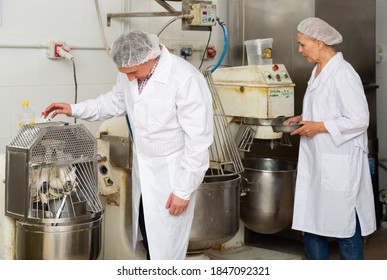 Portrait of two experienced bakery workers watching work of kneading machine making dough - Shutterstock ID 1847092321