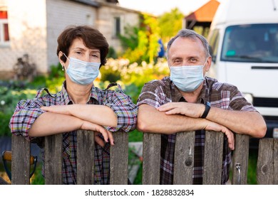 Portrait Of Two Farmers Wearing Protective Masks At The Fence Of Their Country House