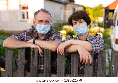 Portrait Of Two Farmers Wearing Protective Masks At The Fence Of Their Country House