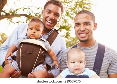 Portrait Of Two Fathers With Baby Carriers In Park