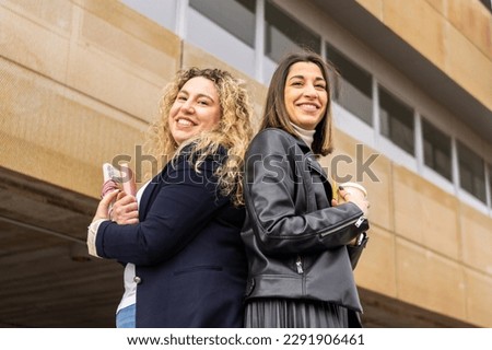 Portrait of two female entrepreneurs with crossed arms outside a building. Portrait of two business women outside a building