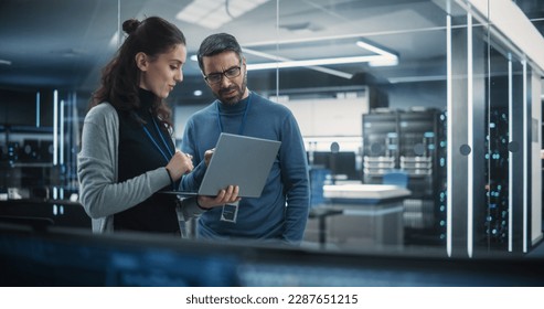 Portrait of Two Female and Male Engineers Using Laptop Computer to Analyze and Discuss How to Proceed with the Artificial Intelligence Software. Casually Chatting in High Tech Research Office - Powered by Shutterstock