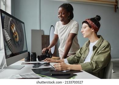 Portrait of two female photographers discussing images on computer screen while working on editing in studio - Powered by Shutterstock