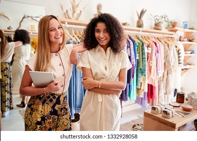 Portrait Of Two Female Sales Assistants With Digital Tablet Working In Clothing And Gift Store