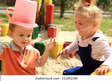 Portrait Of The Two Funny Lovely Kids Playing In The Sandbox