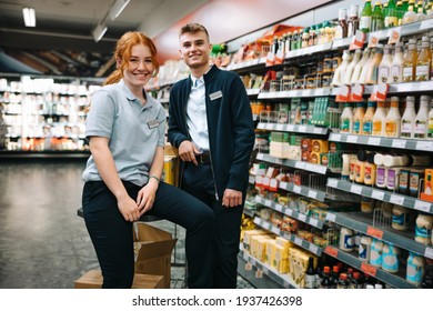 Portrait of two grocery store assistants. Male and female employees smiling at camera in supermarket. - Powered by Shutterstock