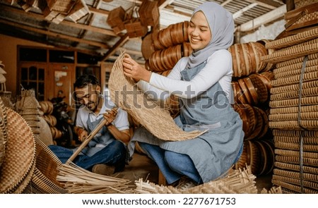 portrait of two handicraft worker is weaving traditional bamboo products in his workshop