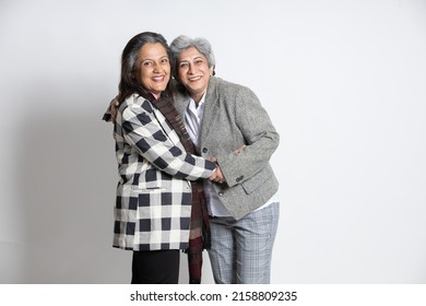 Portrait Of Two Happy Cheerful Mature Senior Indian Businesswoman Colleague Or Co-worker Friends Laughing Hug Together Isolated On White Background. Asian 60s Gray-haired Lady Having A Good Time.