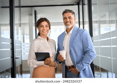 Portrait of two happy executives business man and woman partners in office. Middle aged managers, mature businessman and businesswoman leaders professional team standing at work looking at camera. - Powered by Shutterstock