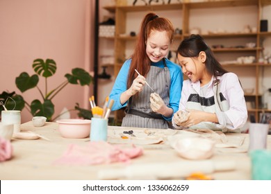 Portrait Of Two Happy Girls Shaping Clay While Making Handmade Ceramics In Pottery Class, Copy Space