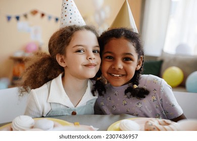 Portrait of two happy little girls looking at camera while enjoying birthday party together. - Powered by Shutterstock