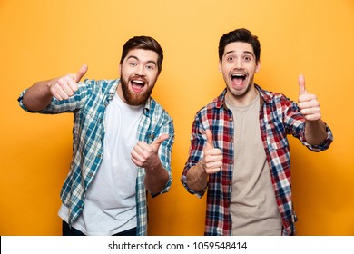 Portrait of a two happy young men standing and showing thumbs up isolated over yellow background - Shutterstock ID 1059548414