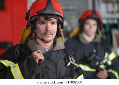 Portrait of two heroic fireman in protective suit and red helmet, second fireman is out of focus, closeup