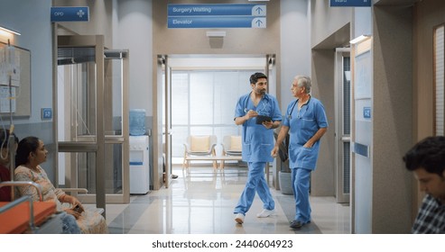 Portrait of Two Indian Male Doctors Walking in Hospital Corridor and Talking while Using a Digital Tablet. Two Medical Specialists Discussing the Treatment of a Patient - Powered by Shutterstock