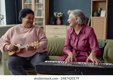 Portrait of two joyful senior women playing music together enjoying creative hobby in retirement home - Powered by Shutterstock