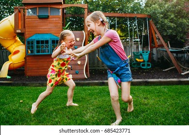 Portrait of  two little girls  sisters fighting on home backyard. Friends girls having fun. Lifestyle candid family moment of siblings quarreling playing together.  - Powered by Shutterstock