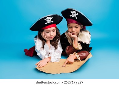 Portrait of two little kids point finger treasure map halloween pirate costume isolated on blue color background - Powered by Shutterstock