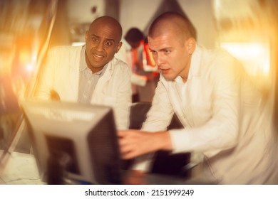 Portrait Of Two Male Friends Trying To Find Solution Of Puzzle Using Computer To Get Out Of Escape Room