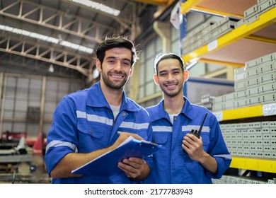 Retrato de dos trabajadores industriales varones que trabajan en la planta de manufactura. Joven y guapo ingeniero de fábrica de la industria masculino usa casco y procesa el orden y el producto en el almacén de manufacturas con felicidad