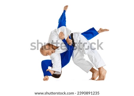 Portrait of two male sportsmen, martial arts fighters in white and blue kimono fighting performing techniques in motions isolated white background. Concept of combat sport, health, energy. Copy space