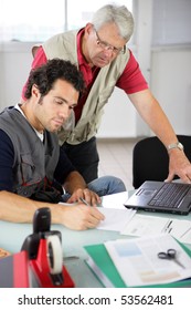 Portrait Of Two Men In Front Of A Laptop Computer Writing On A Document