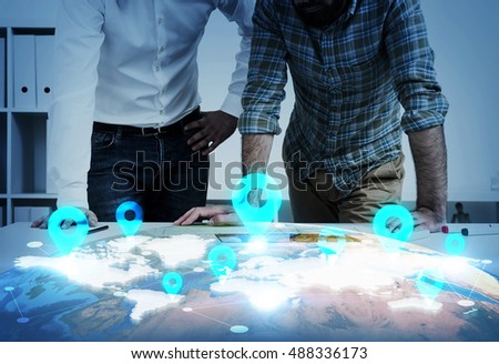 Portrait of two men leaning at table with world map and landmarks on it. Concept of GPS program development.