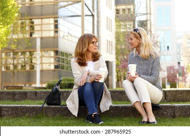 Portrait Of Two Middle Age Women Sitting At Office Park While On Coffee Break. Businesswomen Relaxing While Drinking Coffee And Chatting With Each Other. 