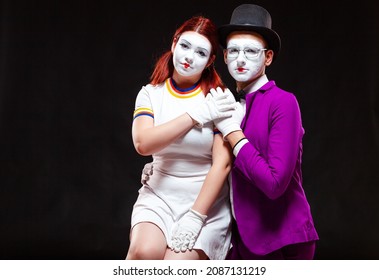 Portrait of two mime artists, isolated on black background. Young woman sits on mans knee. Symbol of family portrait, happy couple