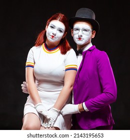 Portrait of two mime artists, isolated on black background. Young woman sits on mans knee. Symbol of family portrait, happy couple