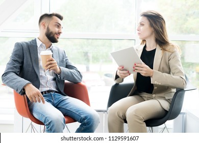 Portrait Of Two Modern Business People, Man And Woman, Sitting In Designer Chairs And Talking To Each Other In Sunlit Room