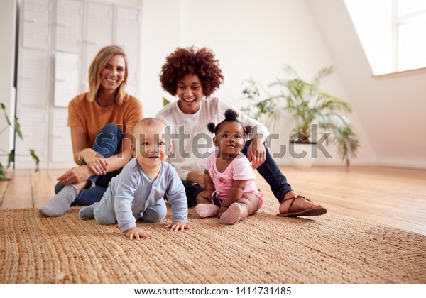 Portrait Of Two Mothers Meeting For Play Date\
With Babies At Home In Loft\
Apartment