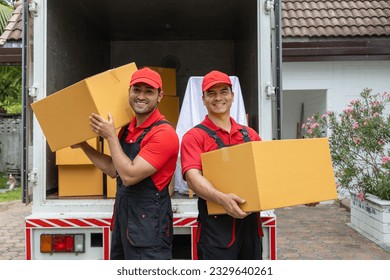 Portrait of two movers unloading boxes and furniture from a pickup truck.