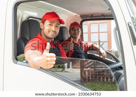 Portrait of two movers unloading boxes and furniture from a pickup truck.