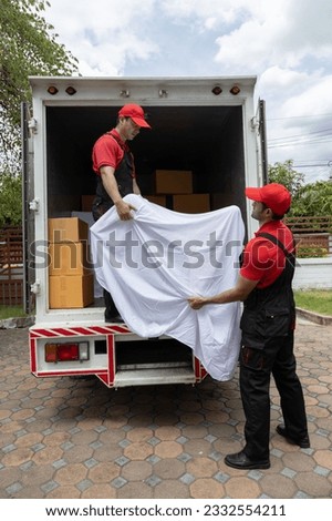 Portrait of two movers unloading boxes and furniture from a pickup truck.
