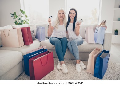 Portrait of two nice attractive lovely pretty cheerful cheery women ordering new clothes things trend web app delivery sitting on divan in light white interior room house flat apartment - Shutterstock ID 1709870041