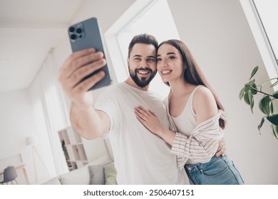 Portrait of two nice young people cuddle take selfie smart phone bright interior free time apartment indoors - Powered by Shutterstock