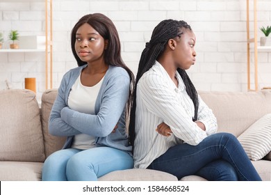 Portrait of two offended black girlfriends sitting back to back, ignoring each other after arguing on sofa at home - Shutterstock ID 1584668524