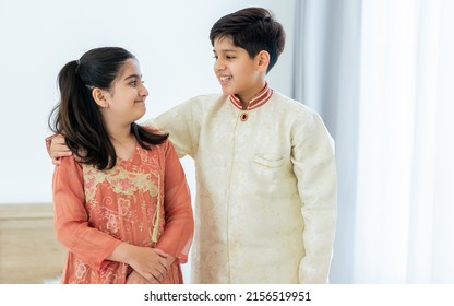 Portrait two people Indian siblings, brother, sister hugging with warmth, love, wearing traditional clothes, smiling with happiness in cozy indoor home. Family, Education, Lifestyle Concept - Shutterstock ID 2156519951