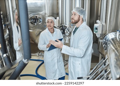 Portrait of two people wearing lab coats inspecting food factory workshop - Powered by Shutterstock