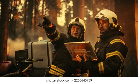 Portrait of Two Professional Firefighters Standing Next to an All-Terrain Vehicle, Using a Heavy-Duty Laptop Computer and Figuring Out a Best Strategy for Extinguishing the Wildland Fire. - Shutterstock ID 2258645739