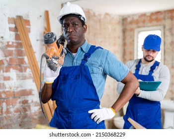 Portrait of two professional workers with an industrial puncher in a building under construction - Shutterstock ID 2150368229