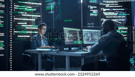 Portrait of Two Programmers Working in a Monitoring Control Room, Surrounded by Big Screens Displaying Lines of Programming Language Code. Portrait of Diverse Developers Creating a Software, Coding