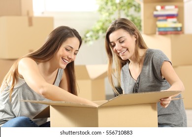 Portrait Of Two Roommates Moving Home Packing Things In A Box Sitting On The Floor