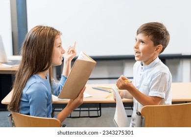 Portrait of two schoolchildren a boy and a girl who are discussing homework, counting aloud and reading write down the subject. The girl as a teacher asks a question the boy answers joyfully - Powered by Shutterstock
