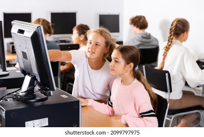 Portrait of two schoolgirls engaged in the classroom at a informatics lesson at the computer
