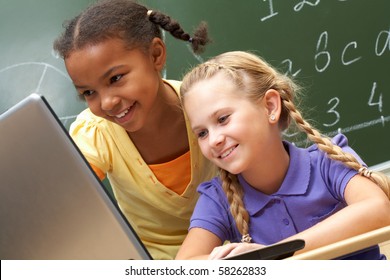 Portrait of two schoolgirls looking at the laptop during lesson