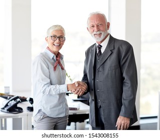 Portrait Of Two Senior Business People Shaking Hands Introducing Each Other In The Office 