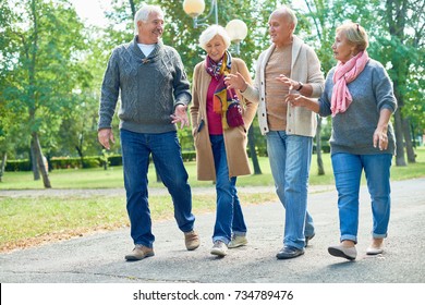 Portrait of two senior couples going for walk in park and smiling happily chatting on the way enjoying sunny autumn day - Powered by Shutterstock